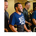 A therapist help guide a smiling man in a back brace and walker